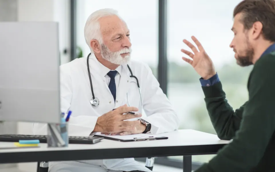 Médico conversa com paciente durante consulta no consultório