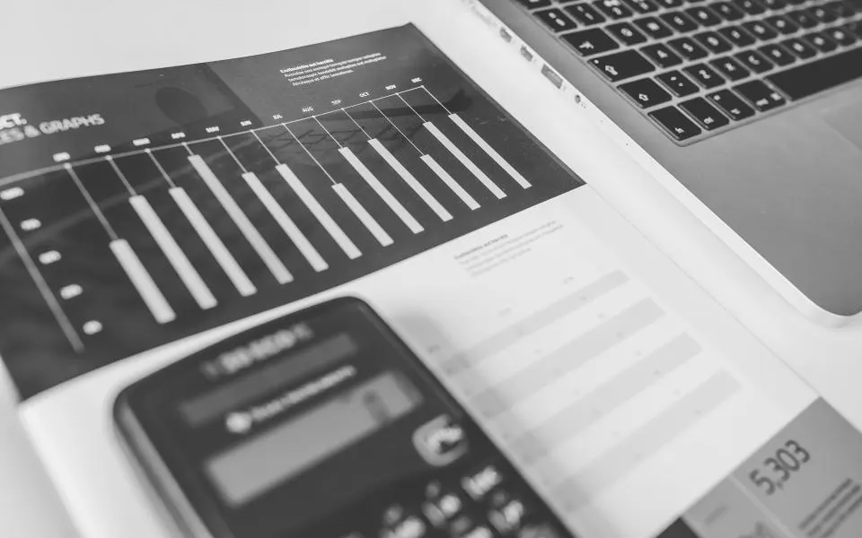 Calculadora e gráficos impressos ao lado de um notebook