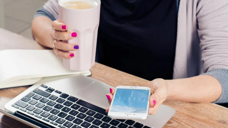 Profissional autônoma organiza a agenda com caderno, celular e notebook