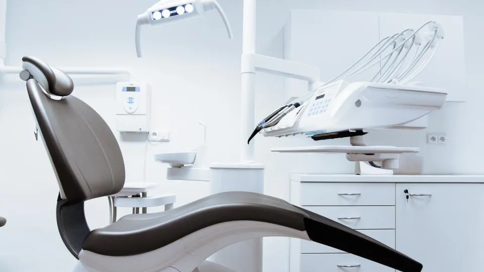 Consultório odontológico moderno e iluminado, com cadeira e equipamentos