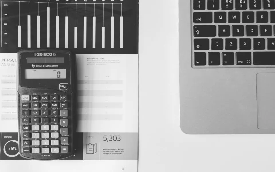Calculadora e relatório impresso ao lado de um notebook